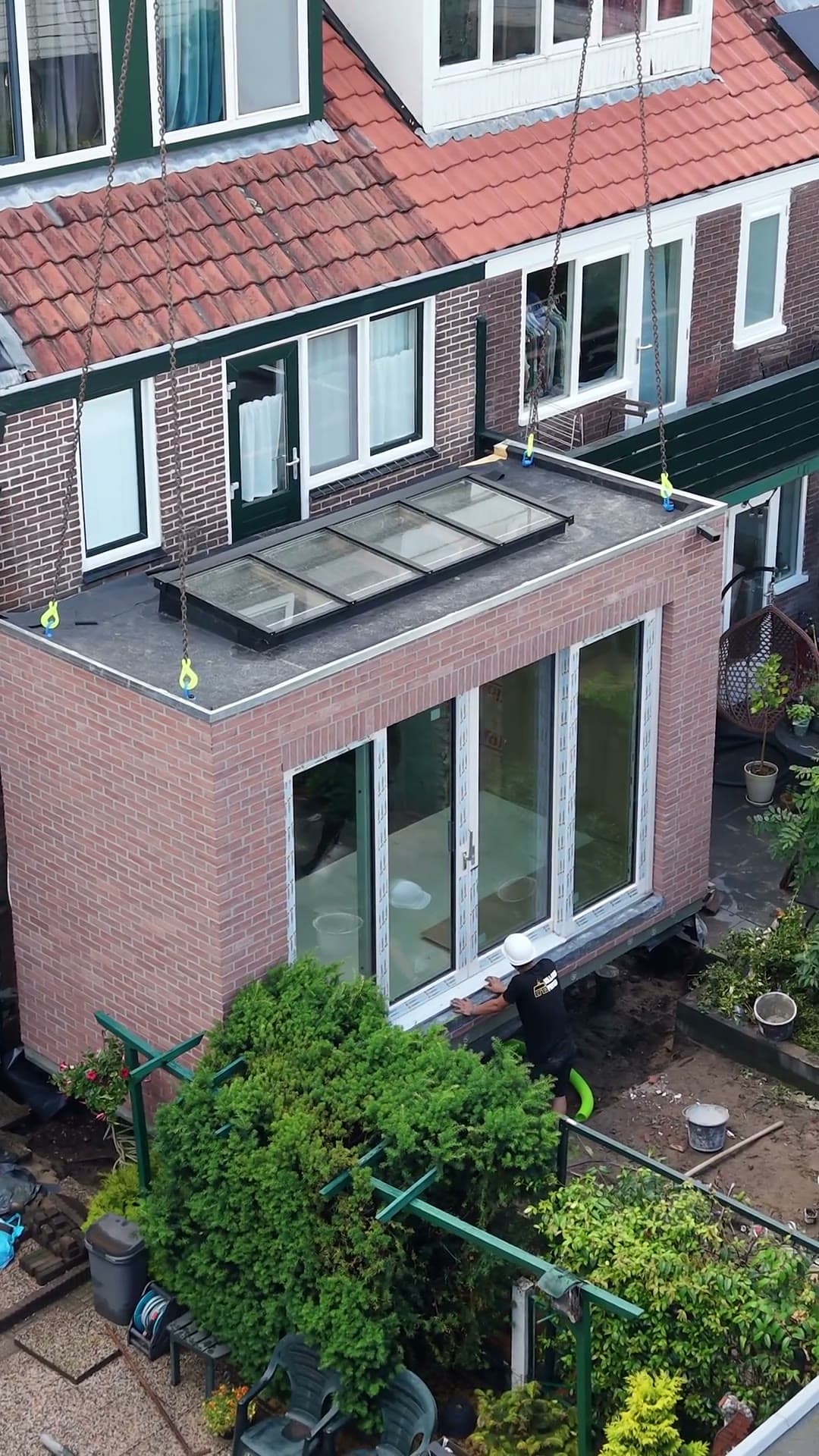 A prefab extension module being craned into a garden